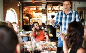 Happy diners at a restaurant smiling and leaving positive reviews on google for restaurant, via smartphones and tablets.